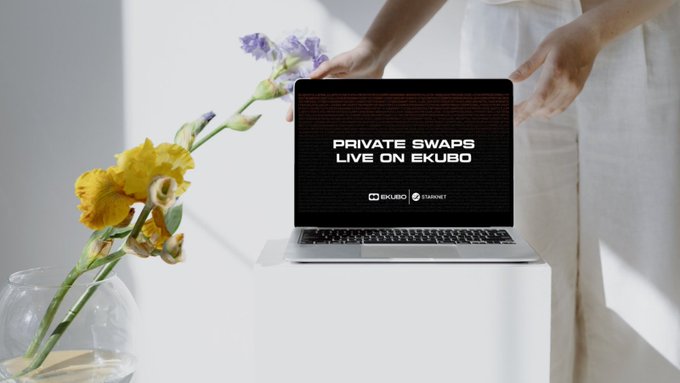 A person in white pants stands beside an open laptop displaying 'PRIVATE SWAPS LIVE ON EKUBO' by Ekubo and Starknet, with a vase of yellow and purple flowers nearby.