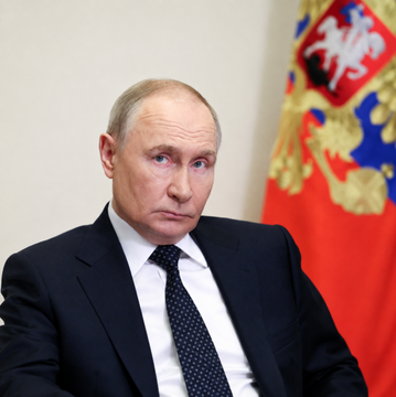 Vladimir Putin is pictured seated in front of a Russian flag, the leader referenced in the breaking news regarding the law he signed that permits retail investors to trade Bitcoin, Ethereum, and USDT.