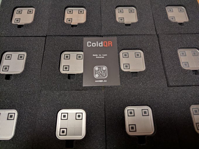 A photograph of numerous ColdQR-branded physical QR code devices arranged in a grid within black foam packaging, with a central card reading 'ColdQR - Made to Last Forever'.