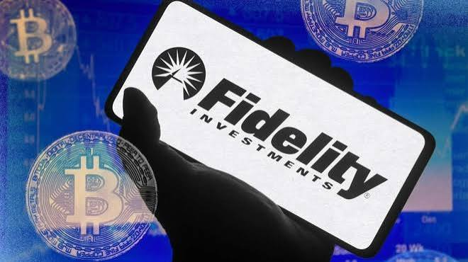 A hand holds a smartphone displaying the Fidelity Investments logo, with gold Bitcoin coins visible in the foreground against a blue background.