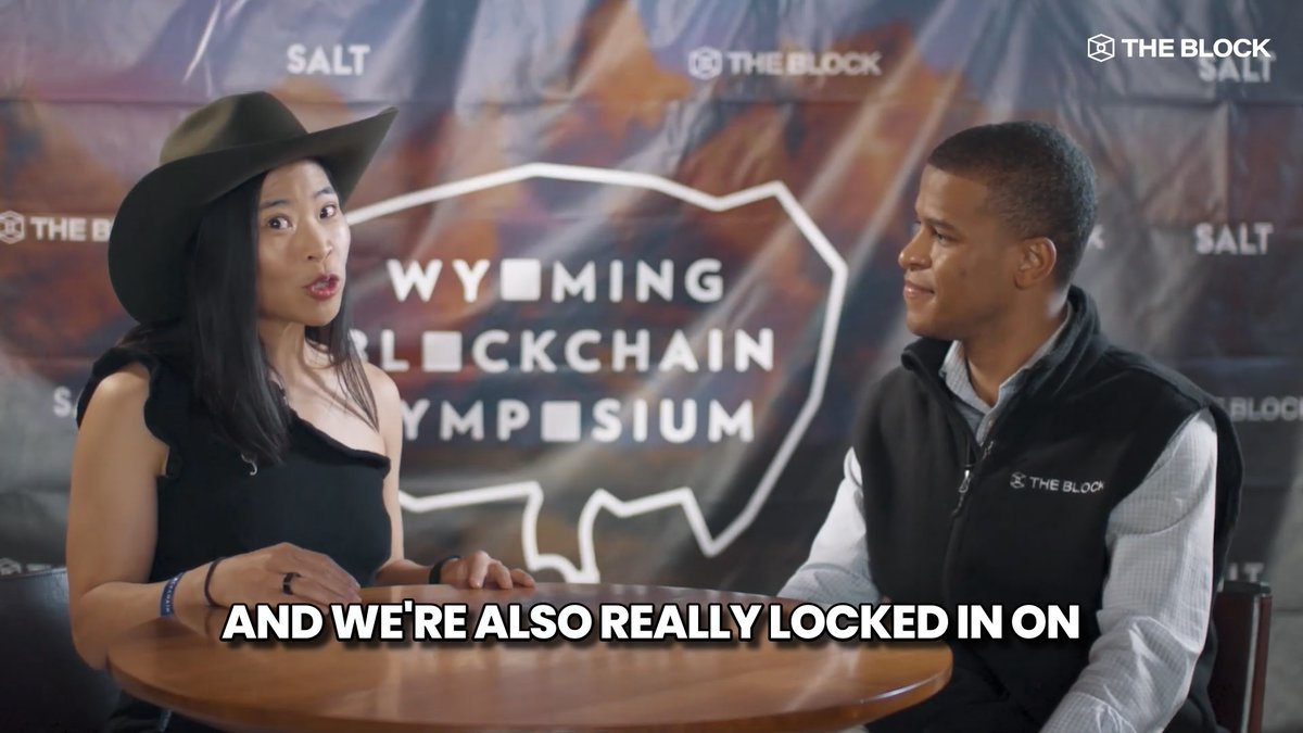 A woman wearing a black cowboy hat and a man in a "The Block" branded vest sit at a table during an interview at the Wyoming Blockchain Symposium, with on-screen text reading "AND WE'RE ALSO REALLY LOCKED IN ON." The scene supports the post's context of an interview where a Filecoin representative discusses the project's evolution from a technically complex experience to a more user-friendly platform.