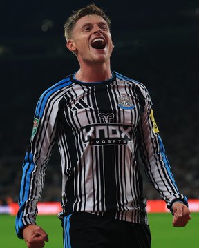 A football player in a black and white striped jersey with 'Knox Sports' branding celebrates with an open-mouthed shout on the pitch.