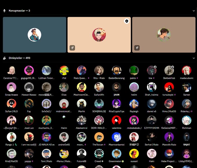 The image shows a large group of people gathered around a computer screen displaying a social media platform called Rialo. The platform has an interface with three different screens, each showing a unique set of profiles or avatars. There are at least 13 distinct profiles visible on the screens, and they all have a similar design featuring circles filled in with various colors representing different types of people. The participants seem to be engaged in discussions about the future of decentralized infrastructure, as indicated by the post that brought them together.