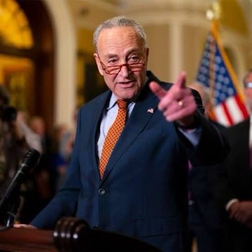 Senate Majority Leader Chuck Schumer stands at a podium, pointing outward, as he convenes a Democratic caucus meeting to discuss the upcoming vote on the Crypto Clarity Act, a key piece of legislation poised to impact the cryptocurrency market.