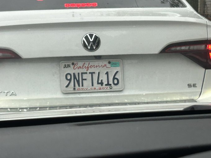 A white Volkswagen sedan displays a California license plate reading '9NFT416' with a JUN 2027 registration sticker.