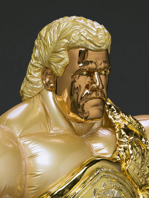 A golden statue resembling a professional wrestler holding a championship belt with 'THE IMMORTAL' visible on the plate.