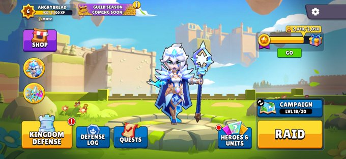 A screenshot from a mobile game showing a player character dressed in ice-themed armor with a staff, standing in front of a castle, with menu buttons like 'KINGDOM DEFENSE', 'DEFENSE LOG', 'QUESTS', and 'RAID' visible.