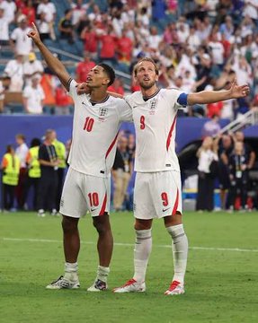 Two England national football team players in white jerseys (#10 and #9) celebrating on the pitch with arms outstretched during a match.