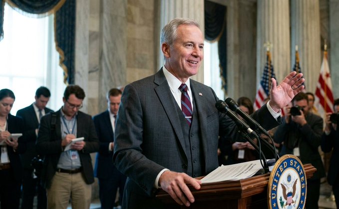 Senator John Thune speaks at a podium adorned with the "United States" seal, surrounded by reporters, suggesting a moment of significant legislative announcement. This image visually represents the "CLARITY ACT UPDATE" mentioned in the post, highlighting the senator's role in potentially passing the bill.