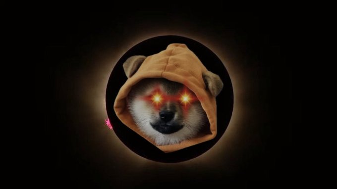 A Shiba Inu dog wearing an orange hood with glowing red eyes on a black background.