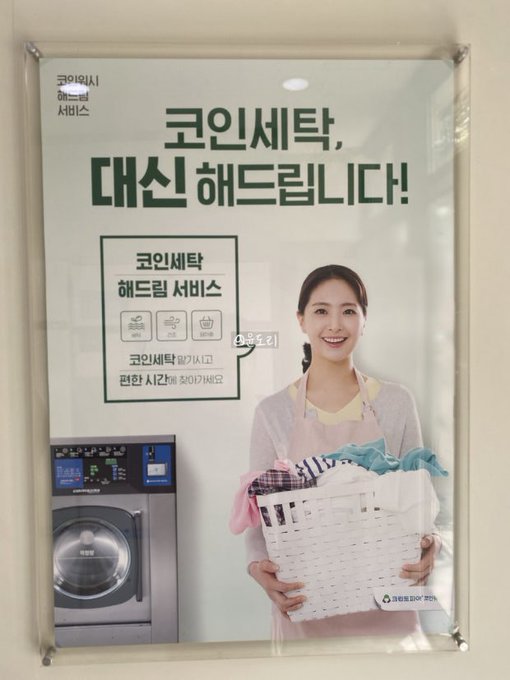 A Korean advertisement poster for a coin laundry service, featuring a smiling woman holding a laundry basket and a Samsung washing machine, with text reading '코인세탁, 대신 해드립니다!' (We do your coin laundry for you!).