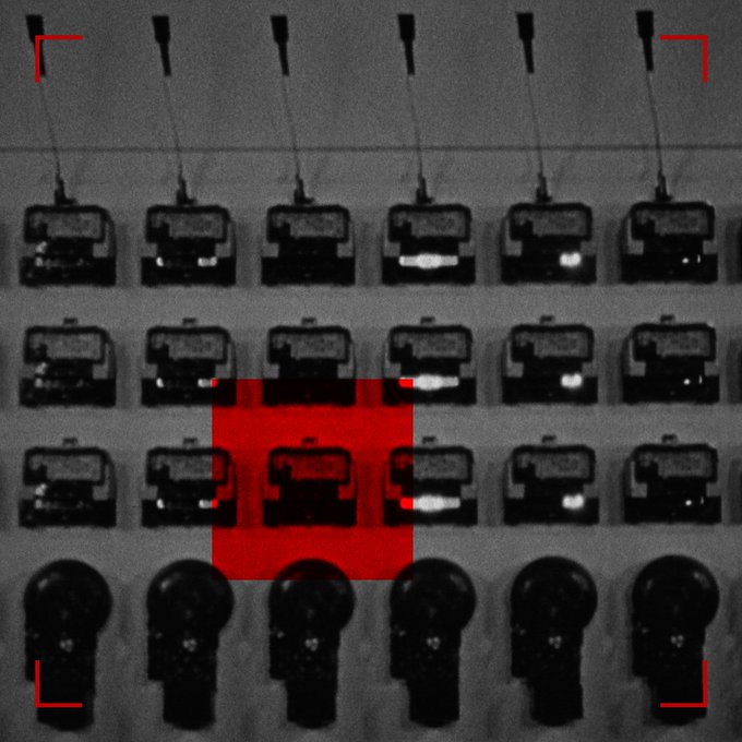 A black and white image of multiple charging docks or devices arranged in rows, with a red square highlighting one section in the middle and red corner brackets framing the scene.