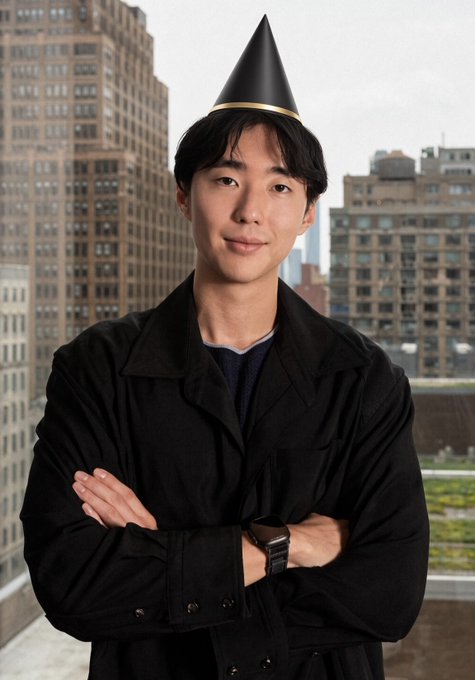 A young man stands confidently with arms crossed in front of a city skyline, wearing a black party hat to celebrate Eric's birthday in relation to his work with Injective. The festive hat symbolizes the celebratory mood of taking the project "to new heights," both literally and figuratively.