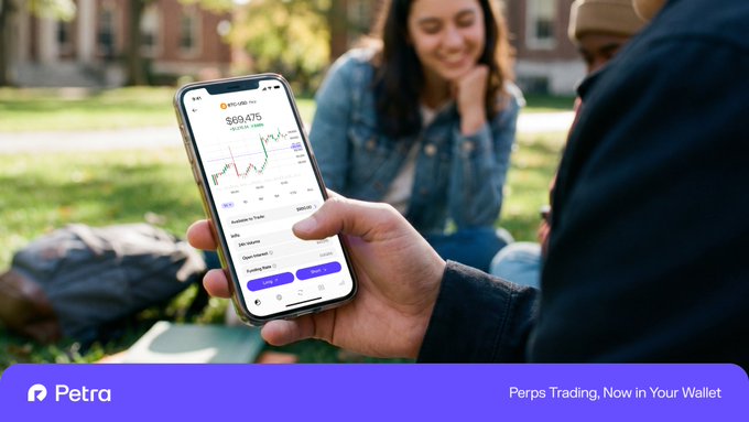 A person holds a smartphone displaying a cryptocurrency trading app showing $69,475 with a price chart, while a smiling woman sits on grass in the background; the ad reads 'Petra - Perps Trading, Now in Your Wallet'.