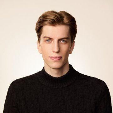A portrait of a young man with light brown hair wearing a black turtleneck sweater against a plain beige background.