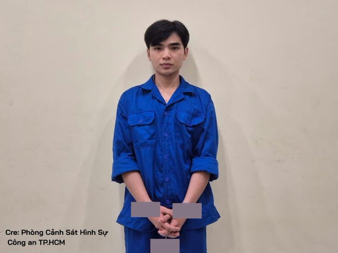 A mugshot-style photo of a young man in a blue button-up shirt with hands cuffed in front, with text "Cre: Phòng Cảnh Sát Hình Sự Công an TP.HCM".