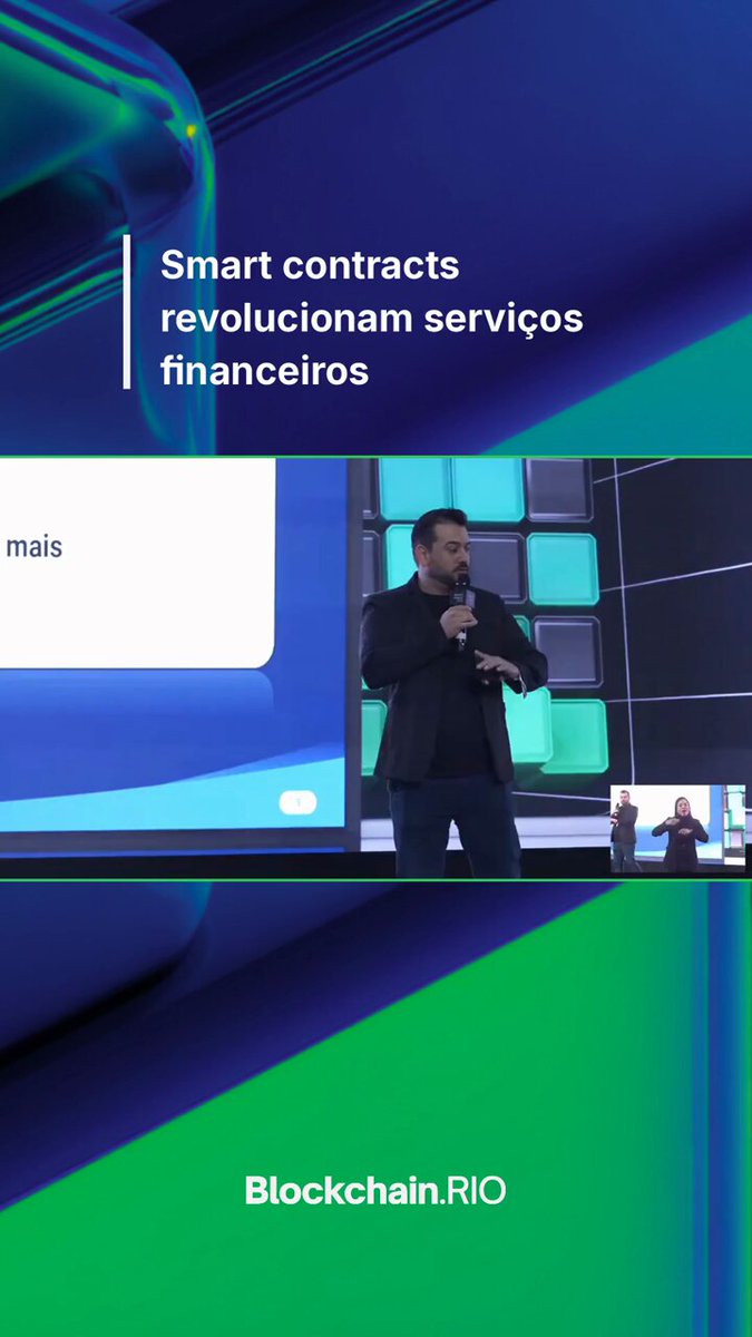 The image features a man standing behind a podium with a presentation slide that says "Smart Contracts Revolutionize Finance" above him. The background of the image shows a blue wall, which has a green border at the bottom. There are two other people in the image who appear to be listening to the presentation or watching it on a screen.