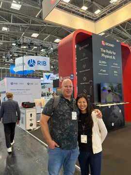 Two people posing together at what appears to be the GITEX technology conference, standing in front of a Geonet booth displaying a sign that reads "The Role for Physical AI."