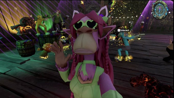 A screenshot from a video game showing a pink-haired character with green heart-shaped sunglasses waving at the camera, with other characters and an 'Interact' prompt visible on a wooden pier.