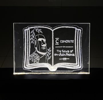 An illuminated acrylic plaque depicts an open book with a portrait and the text 'C | CONCRETE The future of on-chain finance'.