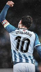 A soccer player wearing a white and blue striped jersey with 'OYARZABAL 10' on the back, raising his fist in celebration during a match.