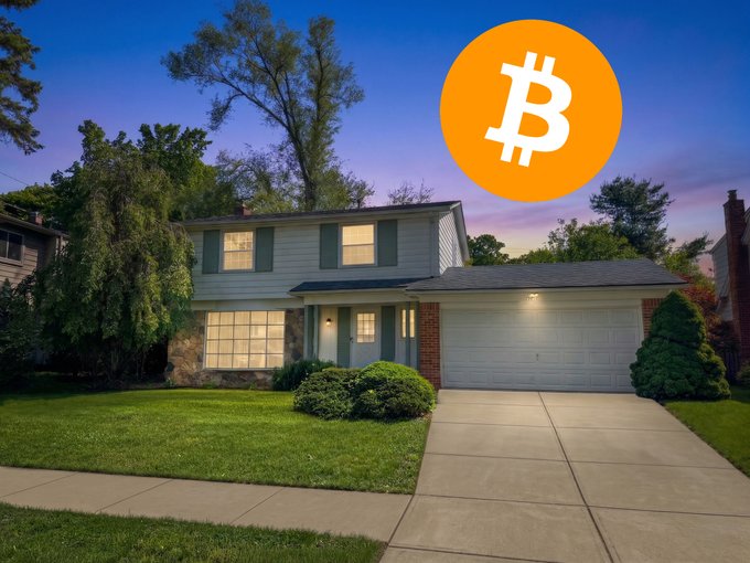 The image shows a house with a garage door and a tree in front of it. The sky above the house has a blue hue at dusk. In the center of the image, there's an orange Bitcoin symbol floating in the air. A caption below the image reads "BREAKING: The first Federal National Mortgage Association-backed mortgage using Bitcoin in the US just closed using Coinbase".
