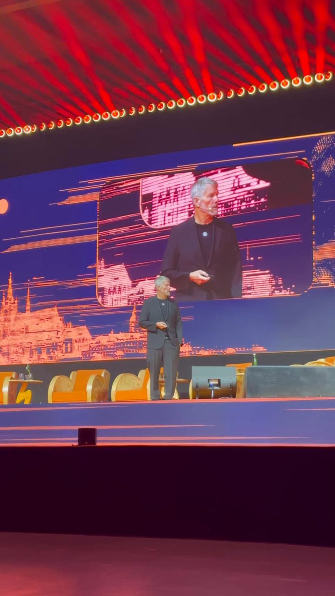 The image shows a man standing on a stage, giving a speech or presentation. He appears to be wearing a suit and tie, suggesting that he might be a professional speaker or presenter. The background of the image features a large screen displaying an image of a man in a suit, possibly representing the main speaker at the event. The caption "BREAKING: @saylor shilling Relai on the main stage" is written below the image, indicating that this is likely a breaking news story related to the event taking place on the stage.