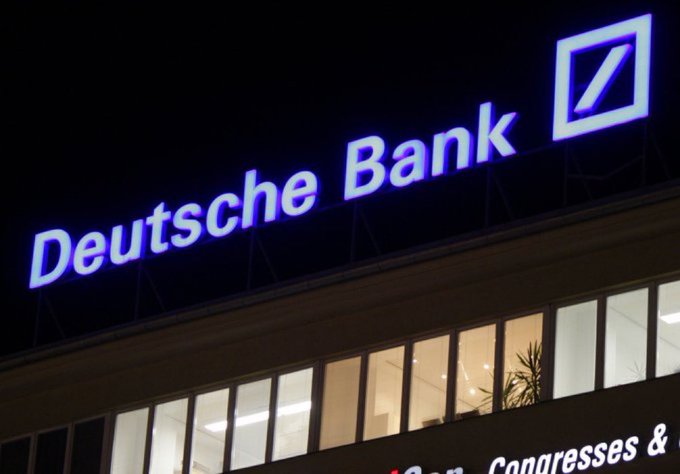 The illuminated "Deutsche Bank" logo and signage atop a building at night, with partial text reading "Congresses &" visible on a banner below. The image visually reinforces the post's claim about Germany's largest bank expanding into crypto custody services as part of growing institutional adoption.