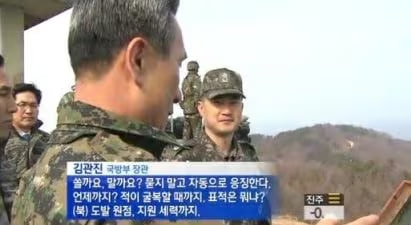 A North Korean military officer speaks to a subordinate outdoors, with Korean subtitles identifying the speaker as 김관진 (Kim Kwan-jin), 국방부 차관.