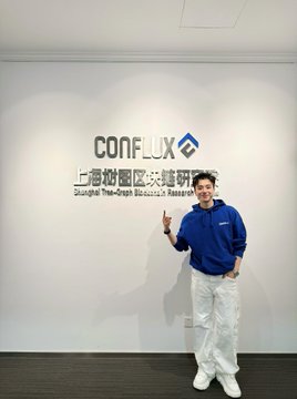 A young man wearing a blue Conflux jacket poses in front of the Conflux Network "Shanghai Tree-Graph Blockchain Research Institute" sign, marking his visit to the only such institute in China.