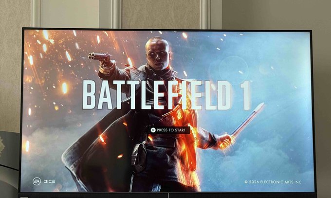 A TV screen displaying the title screen for the video game 'BATTLEFIELD 1' with 'PRESS TO START' button prompt, showing a character holding a pistol and sword with sparks flying.