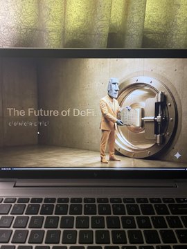 A laptop screen displaying a scene of a person in a suit wearing a cat mask standing in front of a large vault door, with text 'The Future of DeFi' and 'concrete'.