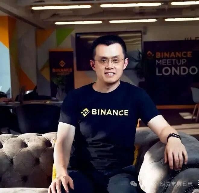 A man wearing glasses and a black 'BINANCE' t-shirt sits on a gray tufted couch in an office setting with a 'BINANCE MEETUP LONDON' banner visible in the background.