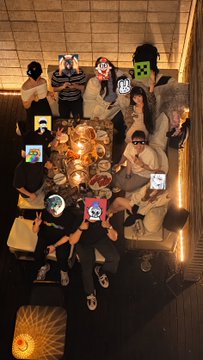 A group of people pose together around a table with various emoji faces overlaid on the image.