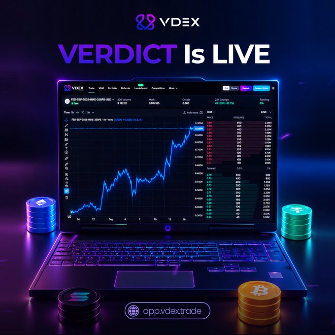 A promotional graphic for 'VDEX' featuring 'VERDICT Is LIVE' above a laptop displaying a stock/crypto trading chart, flanked by stacks of Bitcoin and other cryptocurrency coins.