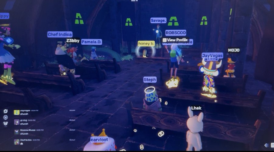 A screenshot of a virtual reality game lobby with a dark, gothic aesthetic, showing multiple avatars with usernames floating above them such as 'Chef Indica', 'ROBSCOO', 'JayVegas', and 'carvloot', alongside a chat box on the left.
