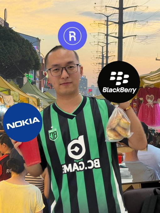 The image features a man wearing a green and black striped jersey, holding up two different logos - one for Nokia and another for Blackberry. The man appears to be posing with these logos, possibly at an event or gathering related to technology or mobile devices.