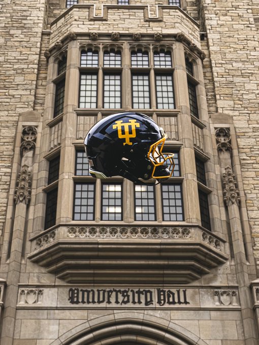 A composite image showing a black and gold football helmet with the IU trident logo floating in front of a Gothic stone building, with 'University Hall' carved above the archway.