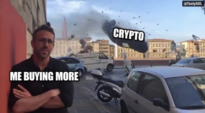 A meme using the 'Ryan Gosling smiling' template shows him labeled 'ME BUYING MORE' calmly observing an explosion labeled 'CRYPTO' on a rooftop.