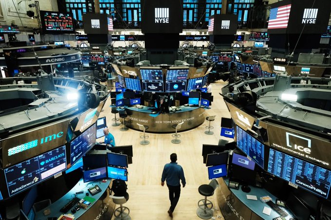 The image shows an inside view of the New York Stock Exchange (NYSE), with numerous computer monitors displaying stock market data. The NYSE has recently partnered with OKX, a crypto exchange, to develop tokenised assets that can be bought and sold on the exchange. This collaboration demonstrates how traditional finance is integrating blockchain technology into its operations for enhanced security and transparency.
