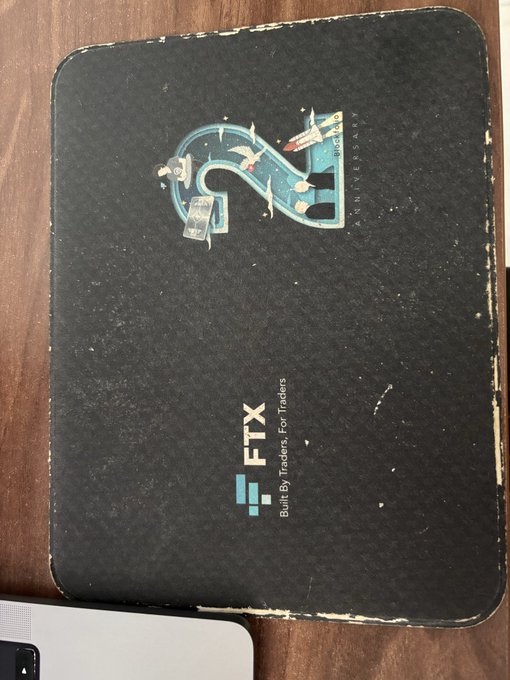 This image shows a well-used FTX 2nd Anniversary mousepad, featuring the "FTX Built By Traders, For Traders" slogan. The battle-worn condition of the mousepad directly relates to the post's theme of FTX merchandise potentially becoming collectible after the exchange's shutdown.