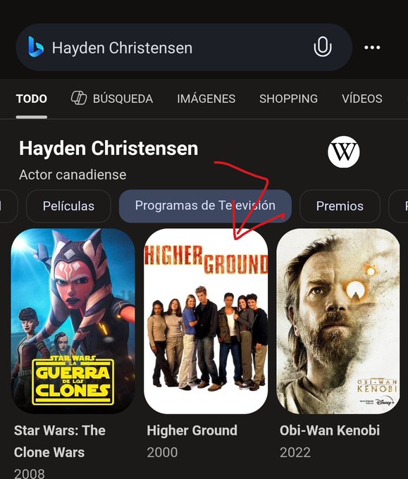 A Bing search results page for 'Hayden Christensen' showing his filmography, with a hand-drawn red arrow pointing toward the 'Programas de Televisión' tab and the movie 'Higher Ground' (2000).