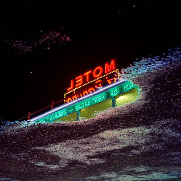 A nighttime photograph of an illuminated 'JETOM' sign, appearing to be a roadside attraction or business.