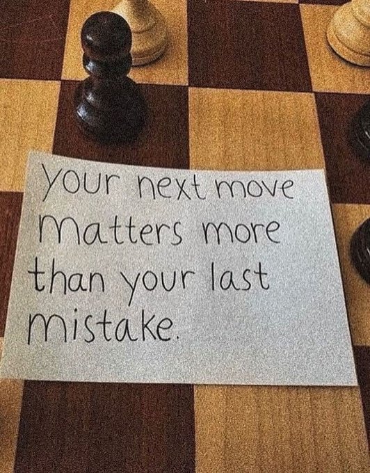 A handwritten note on gray paper placed on a wooden chessboard between black and white chess pieces, reading "your next move matters more than your last mistake."