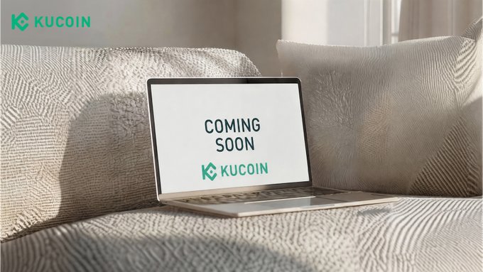 A laptop rests on a soft couch displaying "COMING SOON" alongside the KuCoin logo, with the KuCoin brand also featured in the top-left corner. The image visually teases the platform's upcoming upgrade, reinforcing the post's message that "bigger things are on the way."
