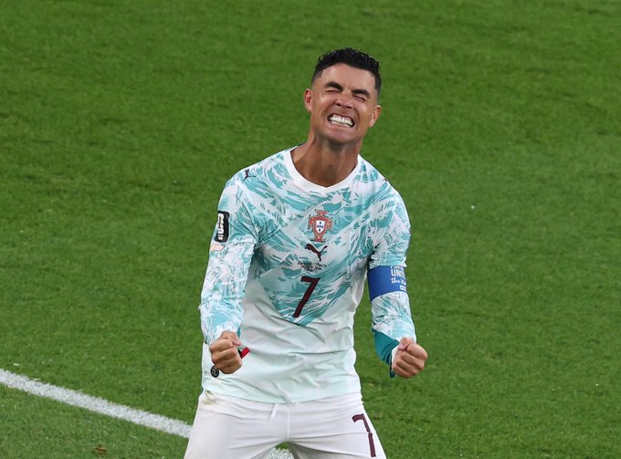 Soccer player Cristiano Ronaldo, wearing Portugal's number 7 jersey with a captain's armband, celebrates with clenched fists on the pitch.