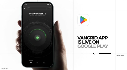 An advertisement showing a hand holding a smartphone displaying the 'UPLOAD ASSETS' screen of an app, alongside text promoting 'VANCGRID APP IS LIVE ON GOOGLE PLAY.'