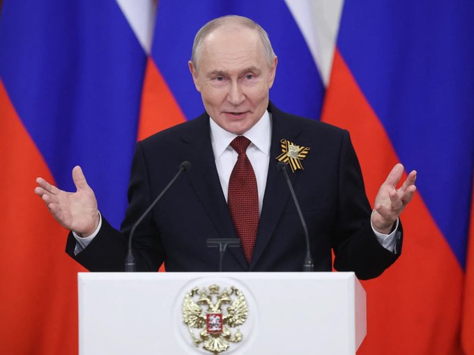 Vladimir Putin, President of Russia, stands at a podium bearing the Russian Federation's coat of arms, gesturing while speaking at a formal address. The image connects to the post by illustrating Russia's move toward regulated crypto exchanges launching on October 5, reflecting the government's ongoing efforts to formalize cryptocurrency access within the country.