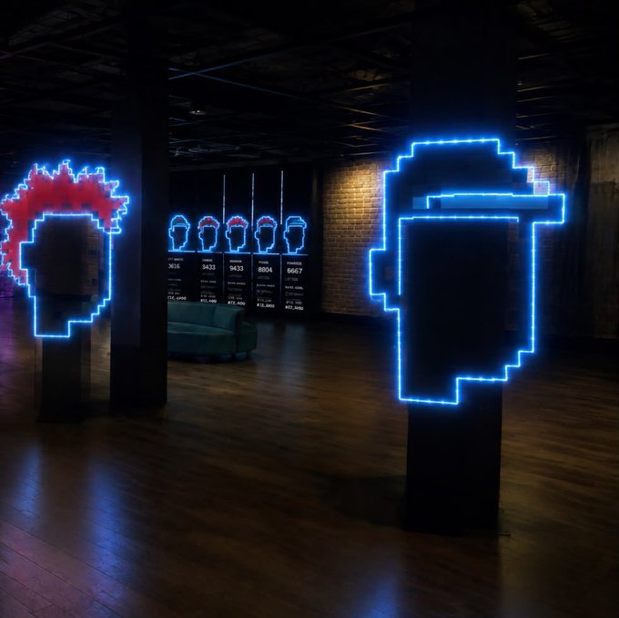 An interior view of a CryptoPunk-themed exhibition space featuring neon-lit 8-bit style portraits, including a red-haired punk and a pipe-smoking figure with pixelated display screens in the background.