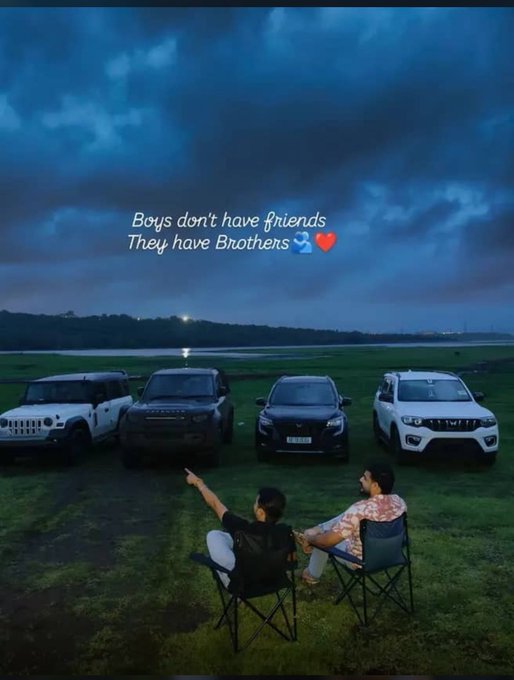 Two people sit in camping chairs facing a lineup of four SUVs on a grassy field at dusk, with the text "Boys don't have friends They have Brothers" displayed alongside water and heart emojis.